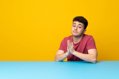 Renkli duvar ve masa genç adamla birlikte palm tutar. Kişi için bir şey sorar