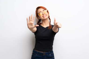 Beyaz duvar altı parmak ile sayma genç Kızıl saçlı kadın