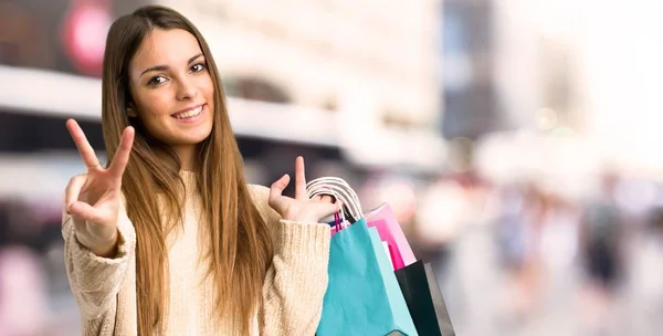 Menina Com Sacos Compras Sorrindo Mostrando Sinal Vitória Cidade — Fotografia de Stock