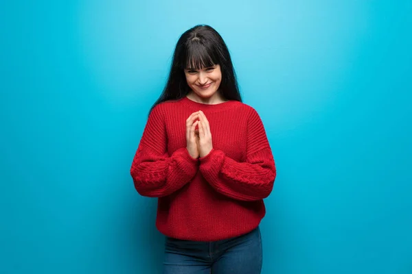 Woman with red sweater over blue wall scheming something