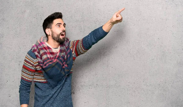Hippie man pointing away over textured wall