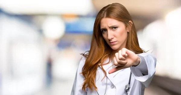 Redhead Läkare Kvinna Visar Tummen Ner Skylten Med Negativa Uttryck — Stockfoto