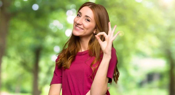 Jonge Roodharige Meisje Tonen Een Teken Met Vingers Het Park — Stockfoto