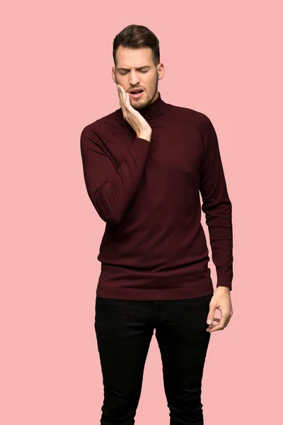 ピンクの背景の上歯痛にタートルネックのセーターを持つ男 — ストック写真