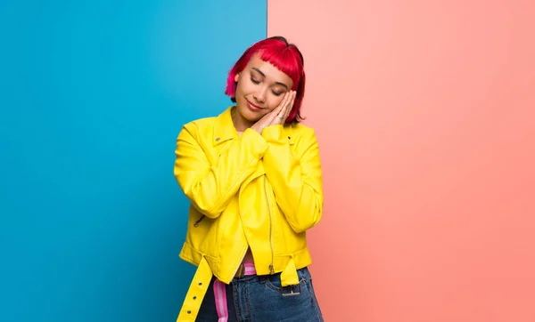 Young woman with yellow jacket making sleep gesture in dorable expression