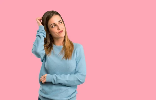 分離ピンク背景に頭を掻きながら疑問を持つ青いシャツとブロンドの女性 — ストック写真
