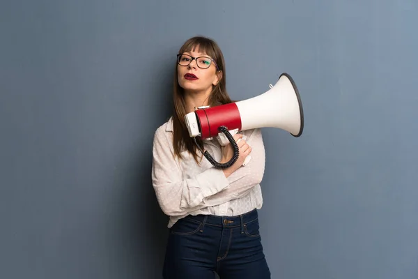 Vrouw Met Bril Blauwe Muur Houdt Een Megafoon — Stockfoto