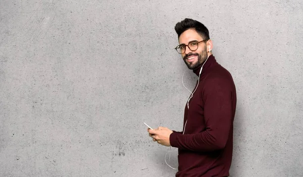 Yakışıklı Adam Gözlüklü Dokulu Duvar Üstüne Mobil Ileti Gönderme — Stok fotoğraf