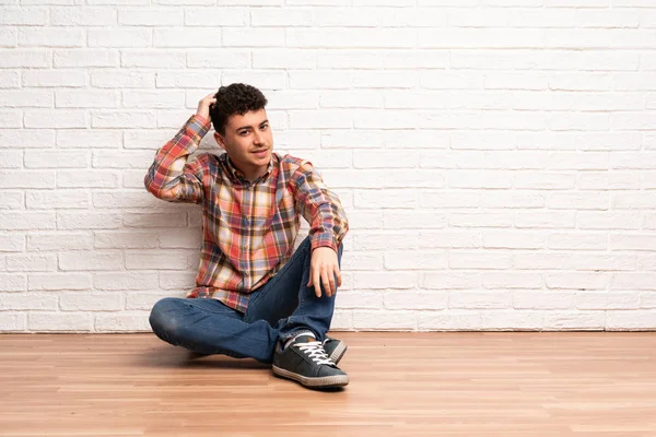 Mladý Muž Sedí Podlaze Pochybnosti Při Poškrábání Hlavu — Stock fotografie