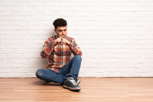 Mladý Muž Sedí Podlaze Ukazuje Znamení Ticha Gesto — Stock fotografie