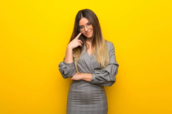 Mujer Joven Con Gafas Sobre Pared Amarilla Mirando Hacia Frente —  Fotos de Stock