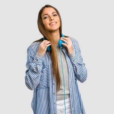 Çizgili gömlekli izole gri arka plan üzerinde kulaklıklarla ile genç kız