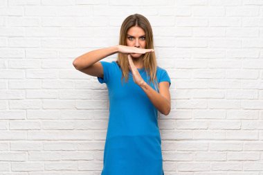 Zaman aşımı jest yapma tuğla duvarın üzerinden mavi elbiseli kadınla