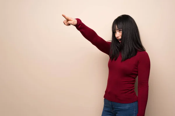 Young woman with red turtleneck pointing away