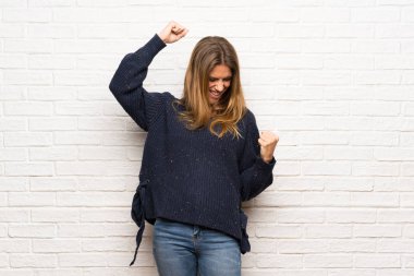 Kazanan konum bir zaferini kutluyor tuğla duvarın üzerinden sarışın kadın