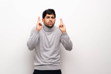 En iyi dilek ve geçiş parmak ile izole beyaz duvar üzerinde genç adam