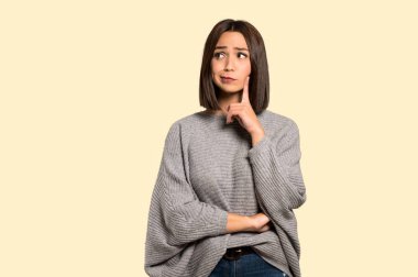 Genç kadın izole sarı arka plan üzerinde düşünme