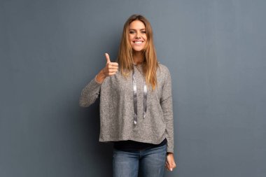 Jest Yaşasın vererek ve gülümseyen gri arka plan üzerinde sarışın kadın