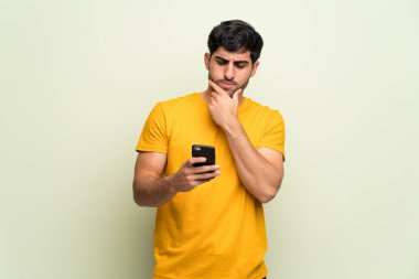 Genç adam bir zafer bir mobil kutlayan pembe duvarın üzerinden