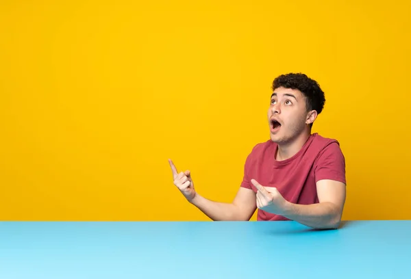 Jovem Com Parede Colorida Mesa Surpreso Apontando Para Cima — Fotografia de Stock