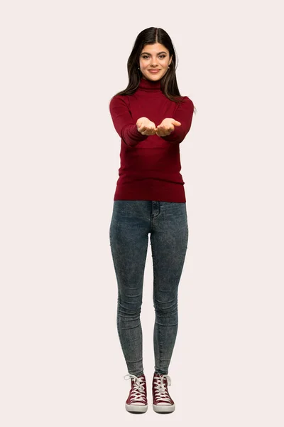 一个少年女孩的全长镜头与高领毛衣持有复制空间想象的手掌插入广告在孤立的背景 — 图库照片