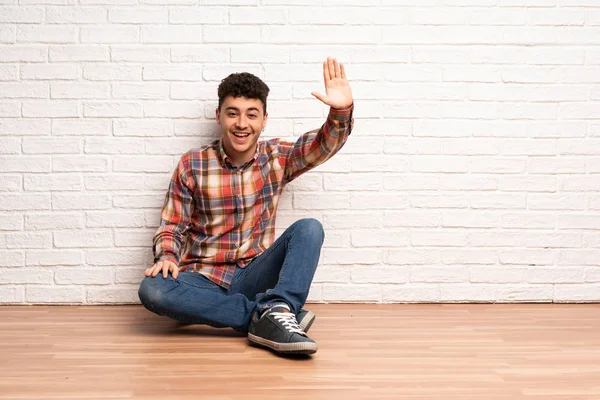 Jonge Man Zittend Vloer Die Met Hand Met Gelukkig Expressie — Stockfoto