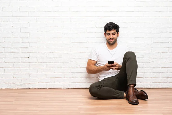 Yerde Oturan Genç Adam Cep Telefonuyla Mesaj Yolluyor — Stok fotoğraf