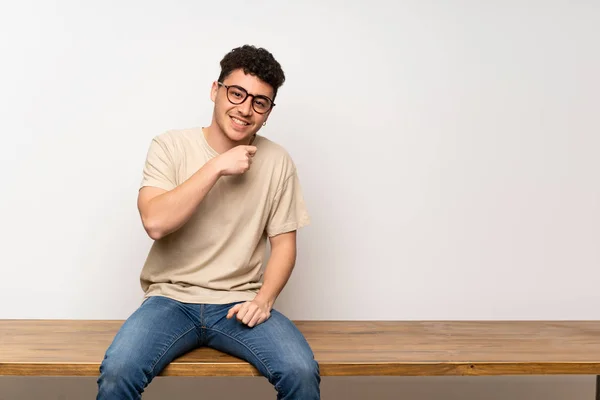 Mladý Muž Sedí Stole Brýlemi Usmívá — Stock fotografie
