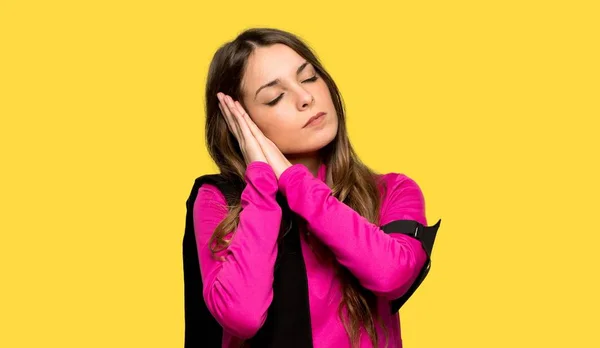 Young sport woman making sleep gesture in dorable expression over isolated yellow background