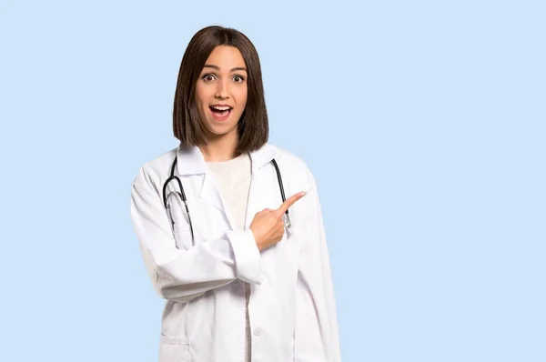 Jonge Dokter Woman Wijzend Naar Kant Een Product Geïsoleerde Blauwe — Stockfoto
