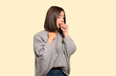 Genç kadın acı ile öksürük ve izole sarı arka plan üzerinde kötü hissediyor