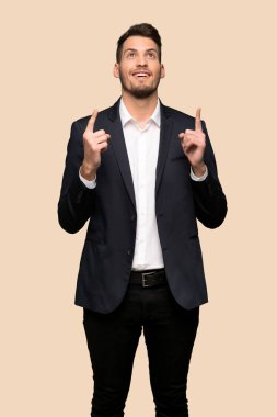Koyu sarı arka plan üzerinde işaret yukarıya ve sürpriz yakışıklı iş adamı