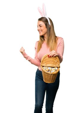 Tavşan kulakları kutluyor zafer ve izole beyaz zemin üzerinde bir ödül kazandığı için mutlu Paskalya tatili için giyen genç kadın