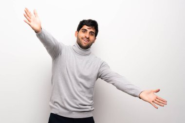 Sunulması ve el ile gelmek davet izole beyaz duvar üzerinde genç adam