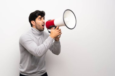 Genç adam bir megafon ile bağırarak izole beyaz duvar üzerinde