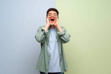 Genç adam bağırıyor ve bir şey ilan mavi ve yeşil arka plan üzerinde