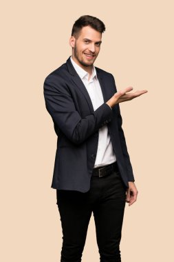 Yakışıklı iş adamı görünümlü doğru koyu sarı arka plan üzerinde gülümseyen iken bir fikir sunmak