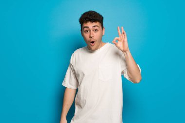 Genç adam arka plan mavi ok işareti sürpriz ve belli