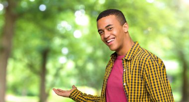 Geri işaret ve bir parkta bir ürün sunma genç afro Amerikalı adam