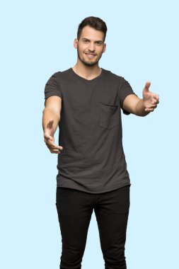 Siyah gömlek sunulması ve mavi arka plan üzerinde el ile gelmek davet adam