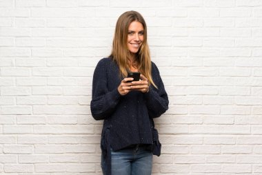 Mobil ileti gönderme tuğla duvarın üzerinden sarışın kadın