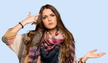 Genç hippi kadın parmak izole mavi arka plan üzerinde kafasına koyarak delilik jest yapma