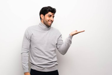 Genç adam boşaltmak hayali avuç içinde tutarak izole beyaz duvarın üzerinden bir reklam eklemek için