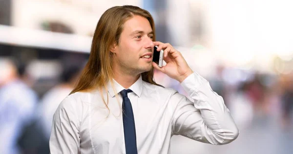 屋外で携帯電話で会話を維持する長い髪のブロンドの実業家 — ストック写真