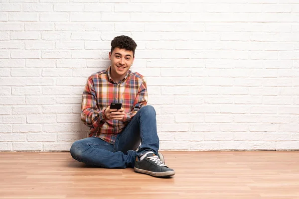 Junger Mann Sitzt Auf Dem Boden Und Sendet Eine Nachricht — Stockfoto