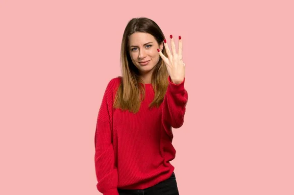 年轻的妇女与红色毛衣愉快和计数四与手指在被隔绝的粉红色背景 — 图库照片