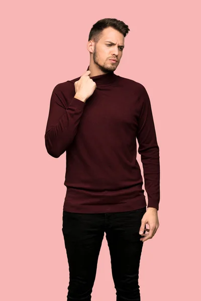 Man with turtleneck sweater with tired and sick expression over pink background