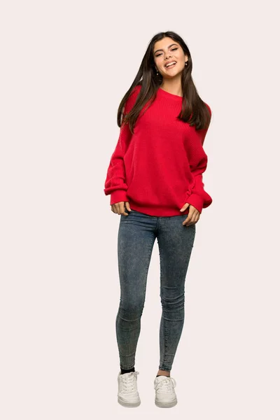 一个穿着红色毛衣的少女的全长照片在孤立的背景上笑着望着前面 — 图库照片