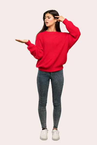 孤立した背景の上 頭に指を置いての狂気のジェスチャーを作る赤いセーターとティーンエイ ジャーの女の子のフルレングス ショット — ストック写真