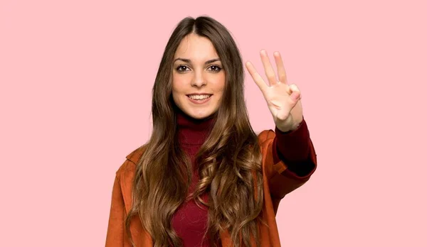 分離ピンク背景の上の指を使ってコート幸せでカウント を持つ若い女性 — ストック写真
